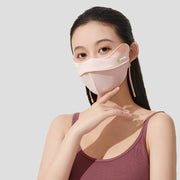 Woman wearing a light pink sun protection face mask on a white background