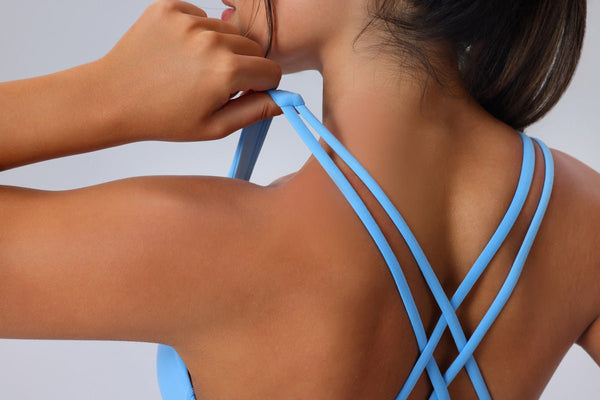 Person wearing a blue strappy top against a light background