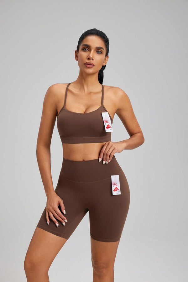 Woman wearing a #brown sports bra and shorts set on a gray background