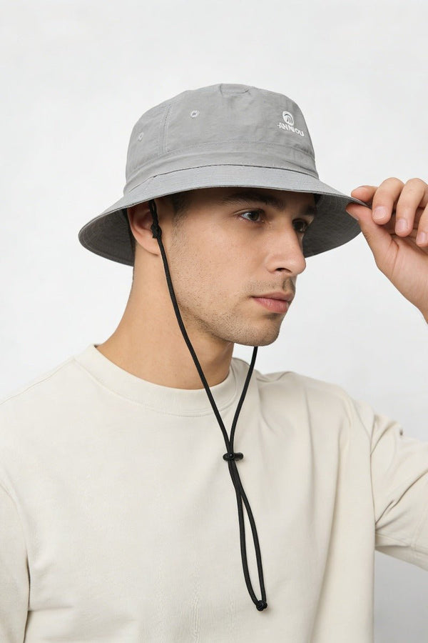 Person wearing a gray bucket hat with a brand logo on a white background