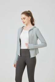 Woman wearing a light gray hoodie and dark gray leggings on a white background. SUN PROTECTION SPORTS HOODED TOP