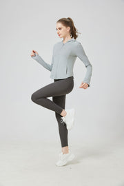 Woman wearing a light gray athletic jacket and dark gray leggings on a white background sun protection set