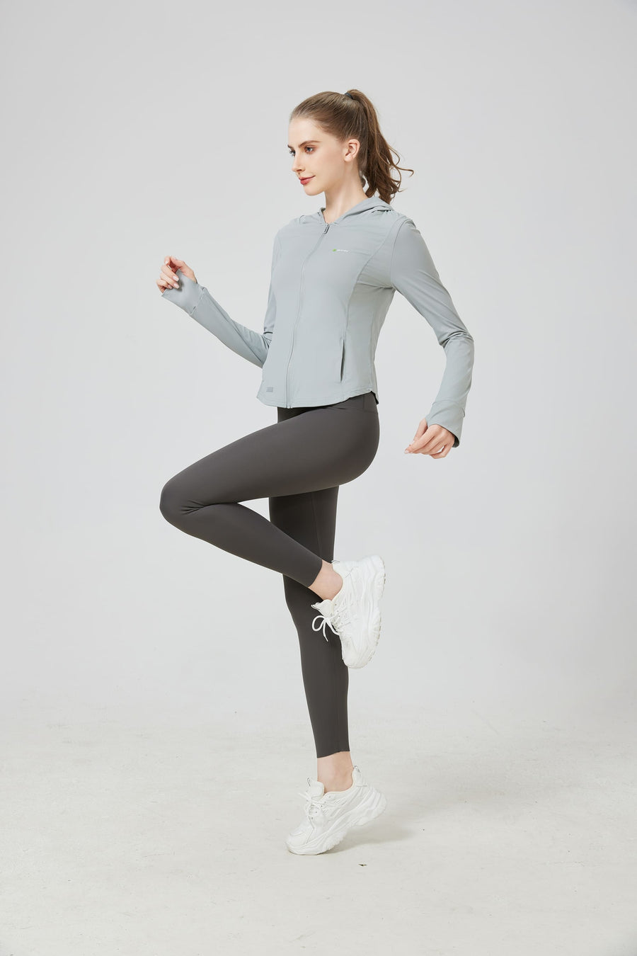 Woman wearing a light gray athletic jacket and dark gray leggings on a white background sun protection set