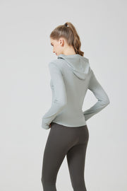 Woman wearing a light gray hoodie and dark gray leggings on a white background