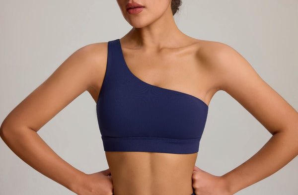 Woman wearing a navy blue sports bra against a neutral background