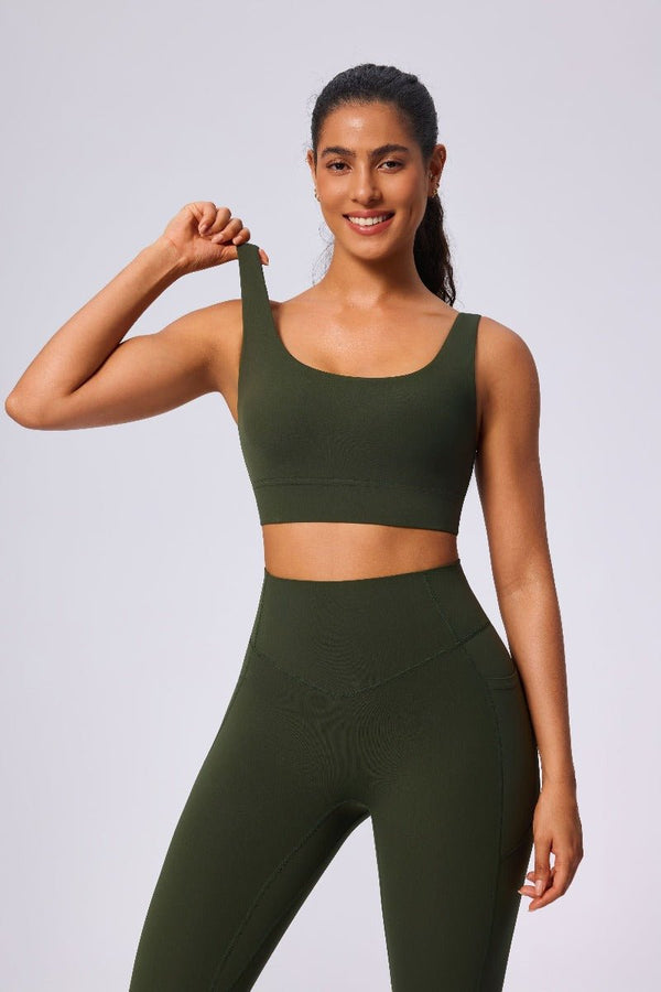 Woman wearing a #green sports bra and leggings on a light gray background