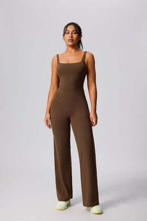 Woman wearing a #brown jumpsuit on a plain background 