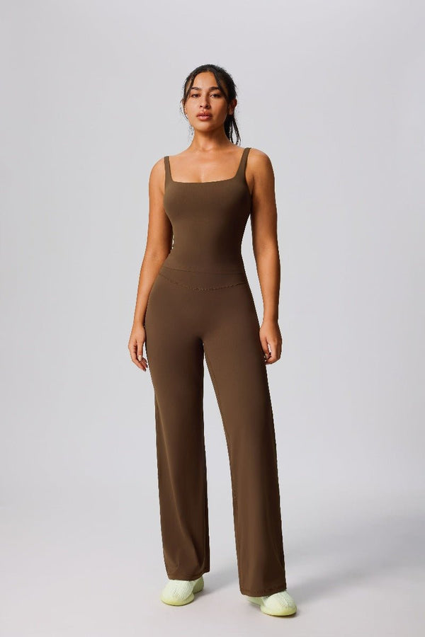 Woman wearing a #brown jumpsuit on a plain background 