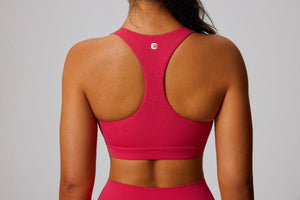 Person wearing a pink sports bra with a brand logo on a gray background