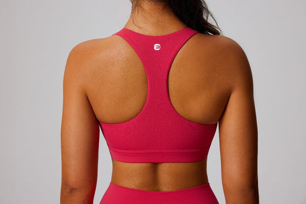 Person wearing a pink sports bra with a brand logo on a gray background