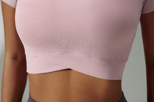 Close-up of a person wearing a light pink athletic top against a neutral background