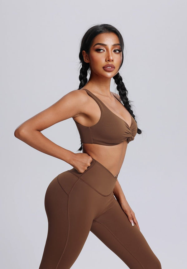 Woman wearing a #brown sports bra and leggings on a plain background