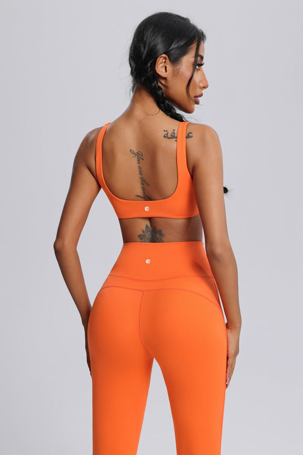 Woman wearing an #orange front twist  sports bra and leggings by Anniou