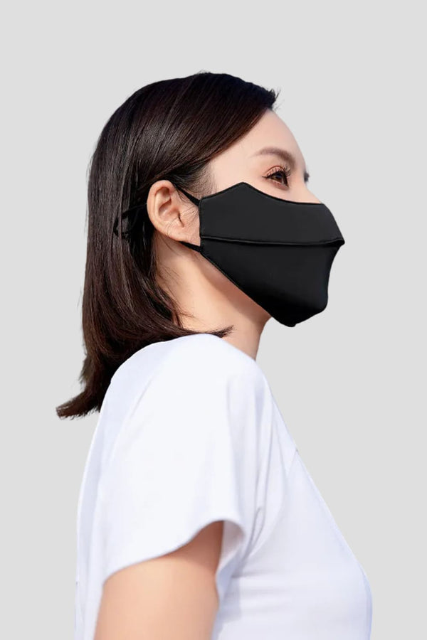 Person wearing a black face mask against a light gray background