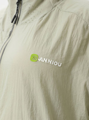 Close-up of a light beige or off-white lightweight jacket fabric with a small green and white ANNIOU logo on the chest.