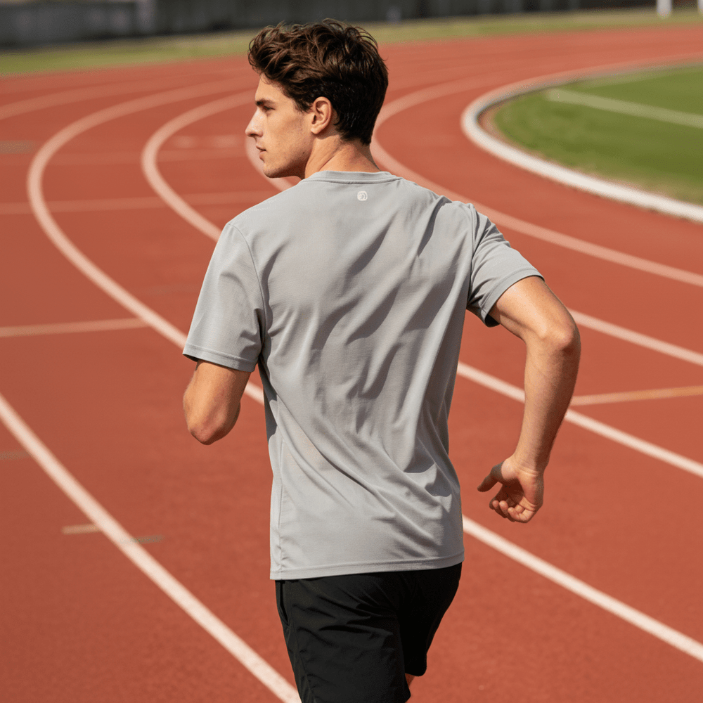 The image shows the back of a gray quick-drying T-shirt, with a sports field in the background.