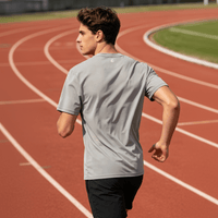The image shows the back of a gray quick-drying T-shirt, with a sports field in the background.
