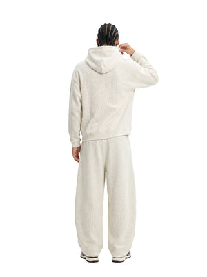 Back view of a male model in an #beige waffle hoodie and matching wide sweatpants against a clean white background.