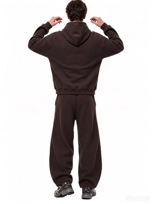 A male model stands in back view with hands raised near his hood, wearing a #coffee waffle-knit hoodie and matching wide sweatpants against a plain white background.