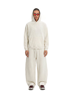 A male model stands front-facing against a plain white background, dressed in an #beige waffle-knit hoodie and matching wide-leg sweatpants.