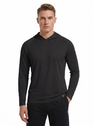 A male model wearing a #black hooded long-sleeve performance shirt and black athletic pants stands against a plain white background. 