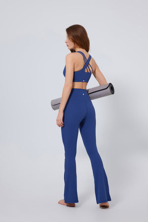 Woman in #navy blue athletic outfit holding a yoga mat with an Anniou sports bra and leggings
