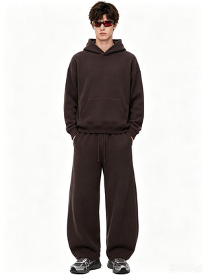 A male model wearing tinted sunglasses stands with hands in pockets against a plain white background, wearing a #Coffee waffle-knit hoodie and matching wide-leg sweatpants.
