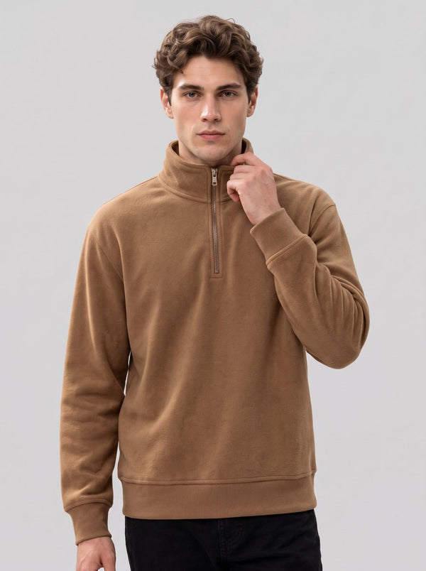 Young male model wearing #coffee half-zip fleece top, one hand gently touching zipper collar, front shot, plain light gray background, men warm fleece sweatshirt