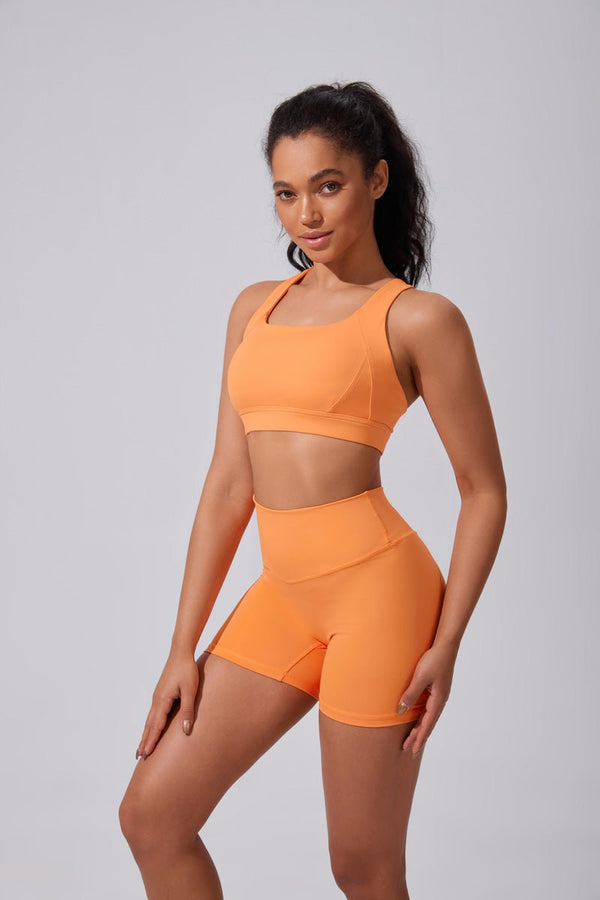 Woman wearing an #orange sports outfit shorts and sports yoga bra