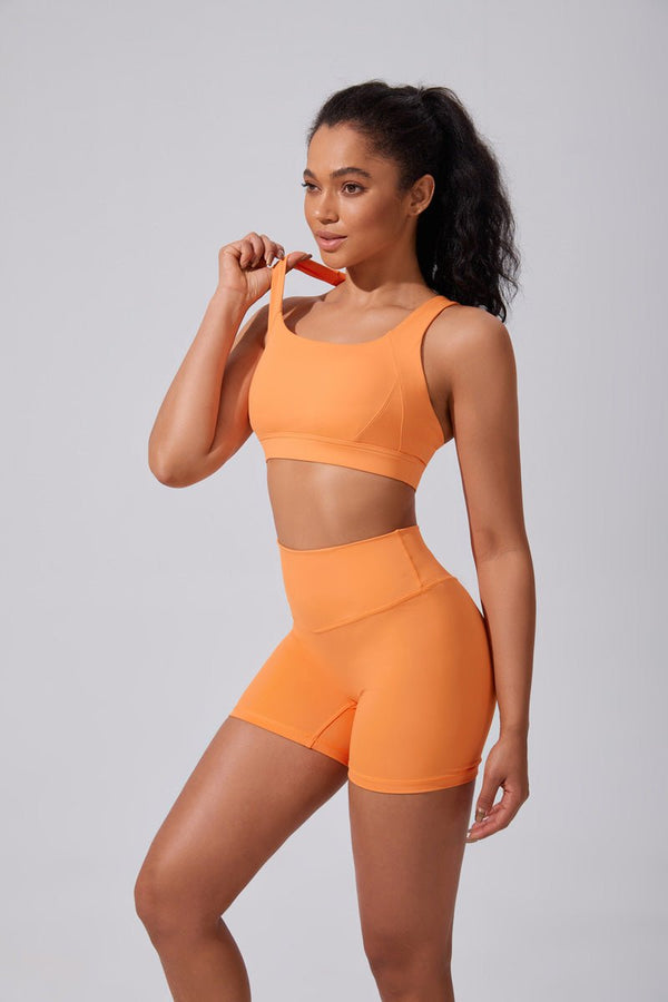 Woman wearing an #orange athletic outfit on a gray background