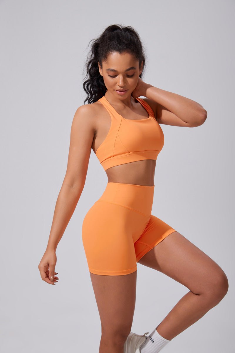 Woman wearing an orange athletic outfit on a gray background