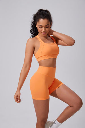Woman wearing an #orange high waist yoga shorts and sports bra