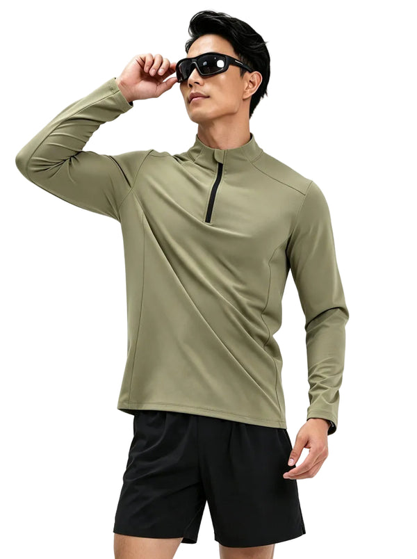 Male model in #green half-zip long sleeve sports top and black shorts adjusting sunglasses, plain background.