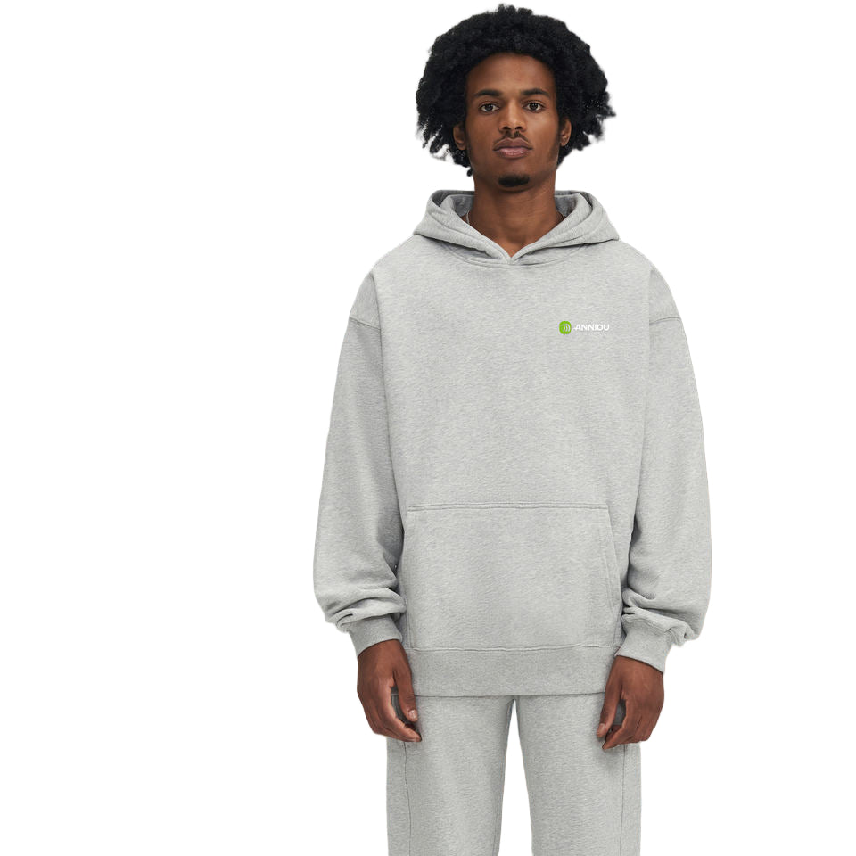 Person wearing a gray hoodie with a brand logo in a snowy forest setting