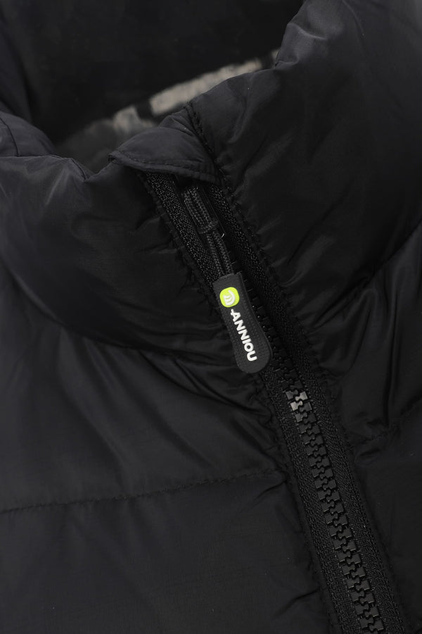 Close-up of a black puffer jacket showing the high collar, quilted fabric texture, and a black zipper pull with a small yellow-green circular logo and white 'ANNIOU' text.
