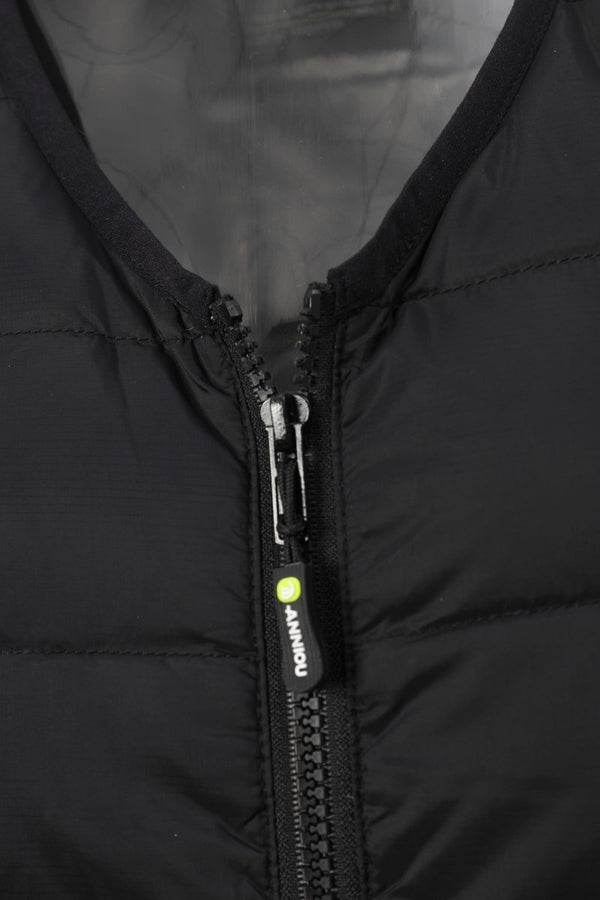 Close-up of a black puffer vest with a black zipper and a small bright yellow-green accent tab on the zipper pull, showing the brand name 'ANNIOU'.