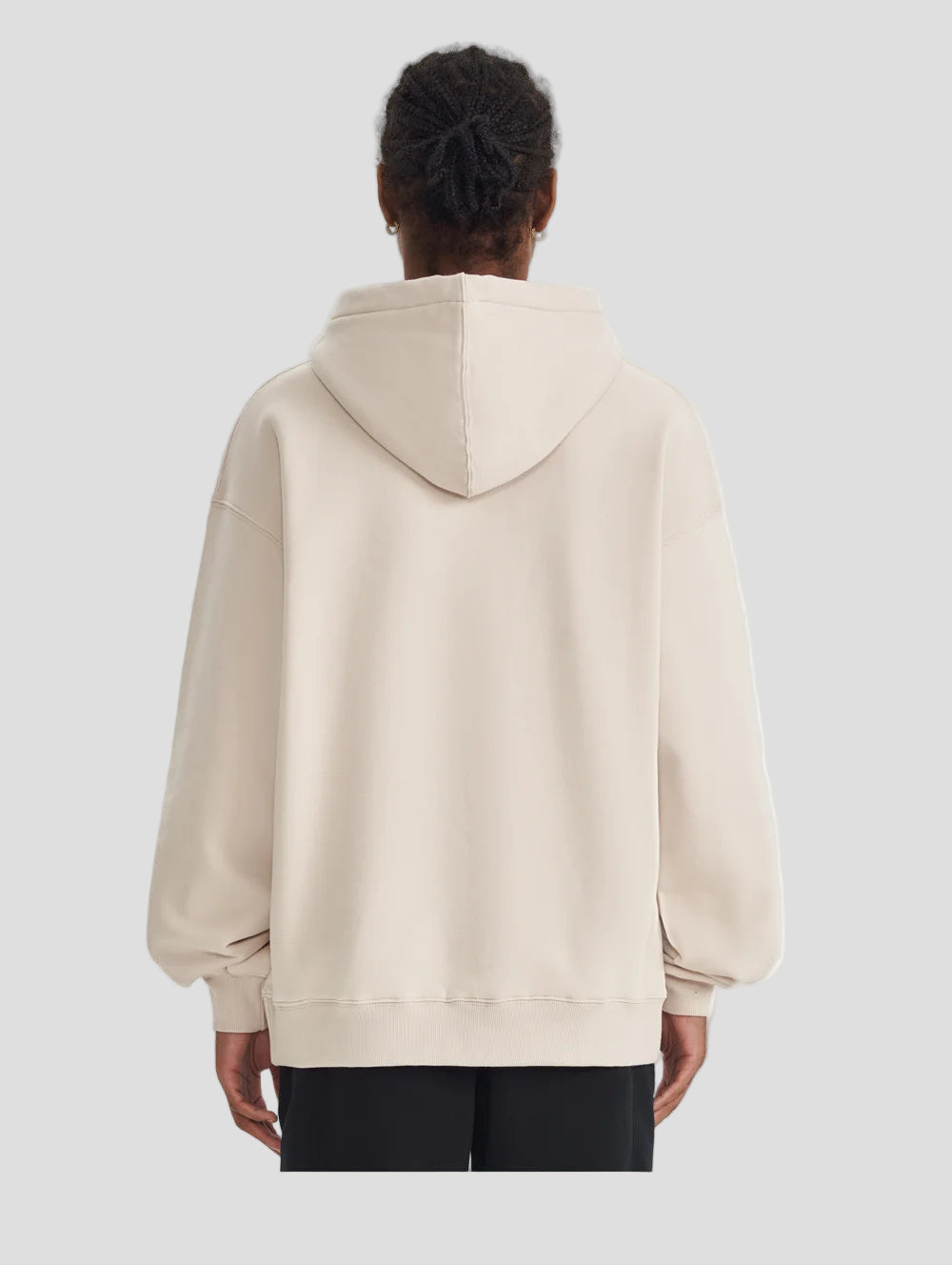 Person wearing a beige hoodie from behind on a light gray background