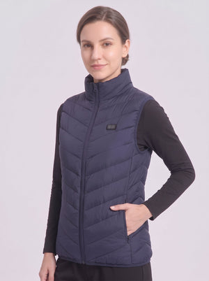 Woman model wearing #navy quilted heated vest, stand collar sleeveless heating gilet with dual control button, one hand in zipper pocket, plain light gray studio background, women winter heated vest product photo