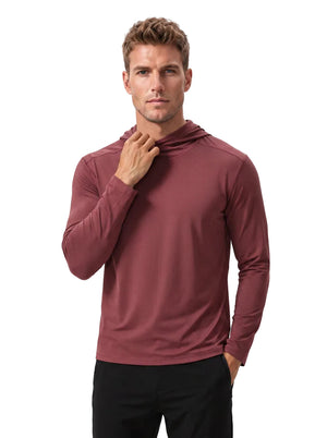 Caucasian male model wearing #maroon hooded long-sleeve performance shirt and black trousers, one hand in pocket while adjusting the collar, plain white background.