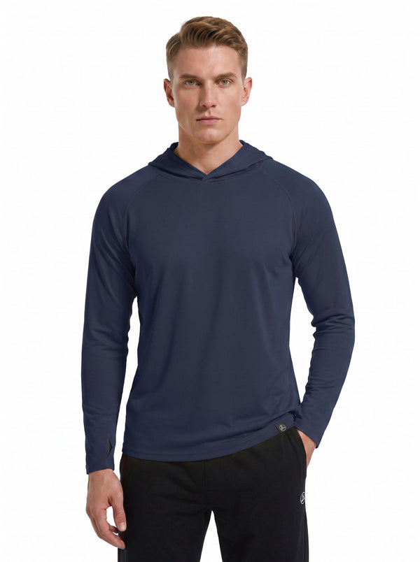 A male model wearing a #navy hooded long-sleeve performance shirt and black athletic pants stands against a plain white background. 