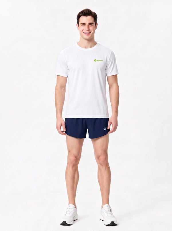 A man stands in a studio wearing a gray short-sleeve athletic T-shirt, navy sports shorts.