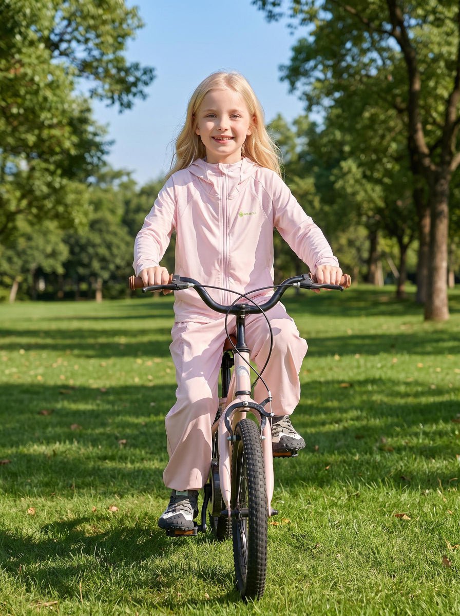 A cute little girl is riding her bike in an outdoor park wearing ANNIOU sun protection gear.