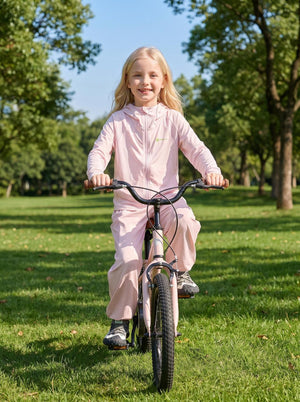 A cute little girl is riding her bike in an outdoor park wearing ANNIOU sun protection gear.