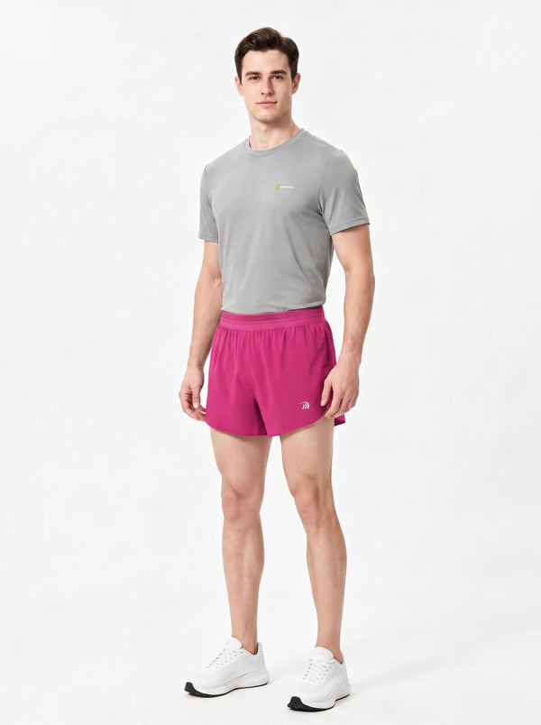 A man stands in a studio wearing a gray short-sleeve athletic T-shirt, rose red sports shorts.