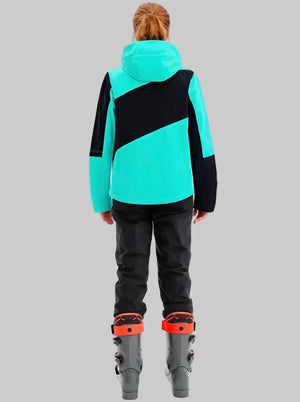 This back-view shot shows a woman wearing a #lakeblue hooded ski jacket paired with black ski trousers. She stands in ski boots, showcasing the sleek color-block design and tailored cut of the snow suit.
