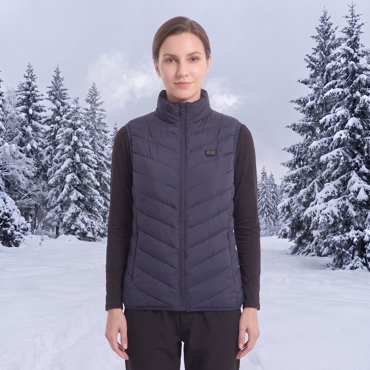 Female model wearing navy quilted heated vest, standing in snowy pine forest, cold winter outdoor scene, women insulated heating vest lifestyle photo