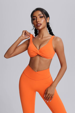 Woman wearing an #orange front twist  sports bra and leggings