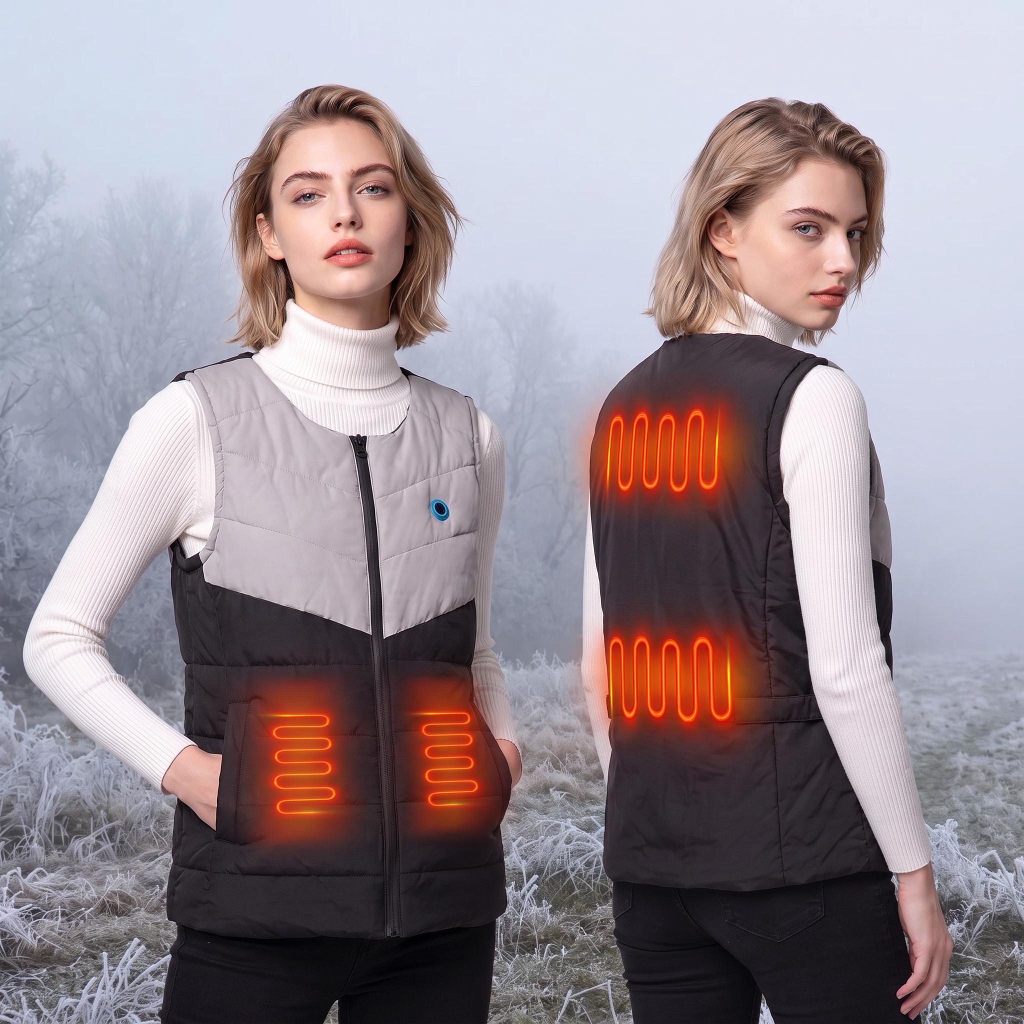 Two views of a young European female model in a two‑tone grey‑black heated gilet. Front and back are displayed, with glowing orange heating coil illustrations showing heating zones on waist pockets and back panel. Set against a frosty, misty winter outdoor backdrop with frost‑covered vegetation.