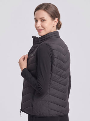 female model wearing #black quilted heated vest, stand collar, hand holding zipper, light gray studio background, women winter heated gilet product photography