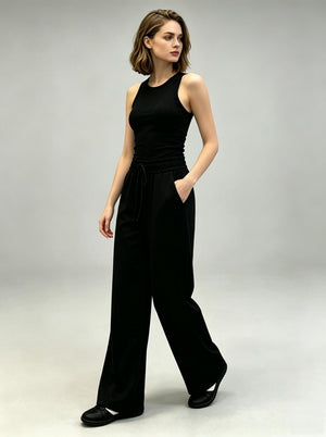 Female model walking in #black ribbed tank top and black drawstring wide leg casual pants, 